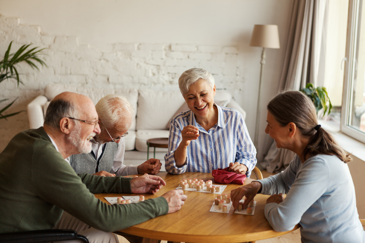 Quatre résidents qui rient ensemble autour d’une table de bingo
